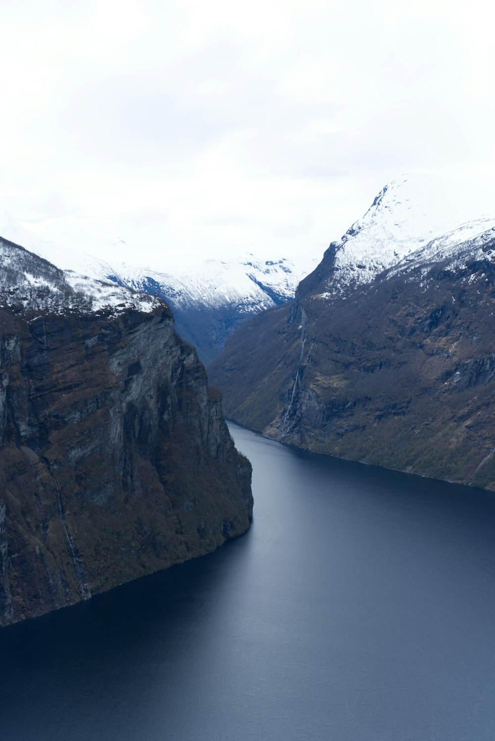 snow covered mountain beside body of water during daytime