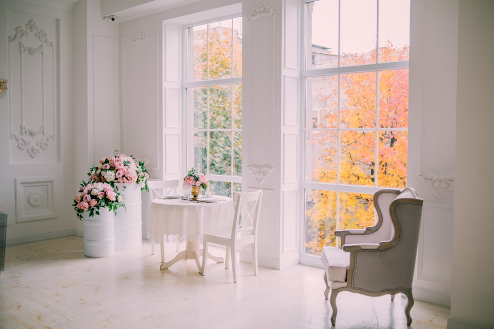 white wooden table with chairs near white wooden framed glass window