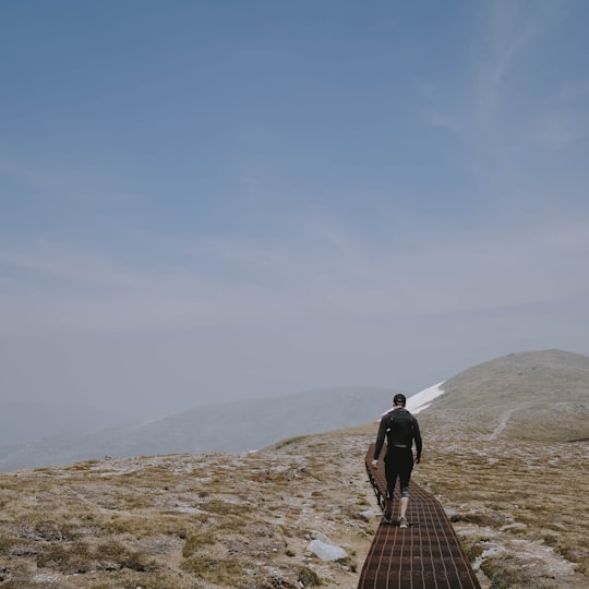 man in black jacket and brown pants standing on brown wooden pathway during daytime in Kosciuszko National Park NSW Australia