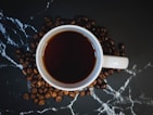 white ceramic mug with coffee on black and white textile
