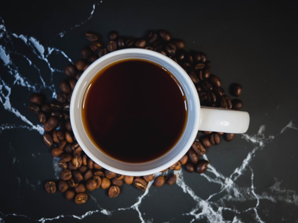 Tazza in ceramica bianca con caffè su tessuto bianco e nero