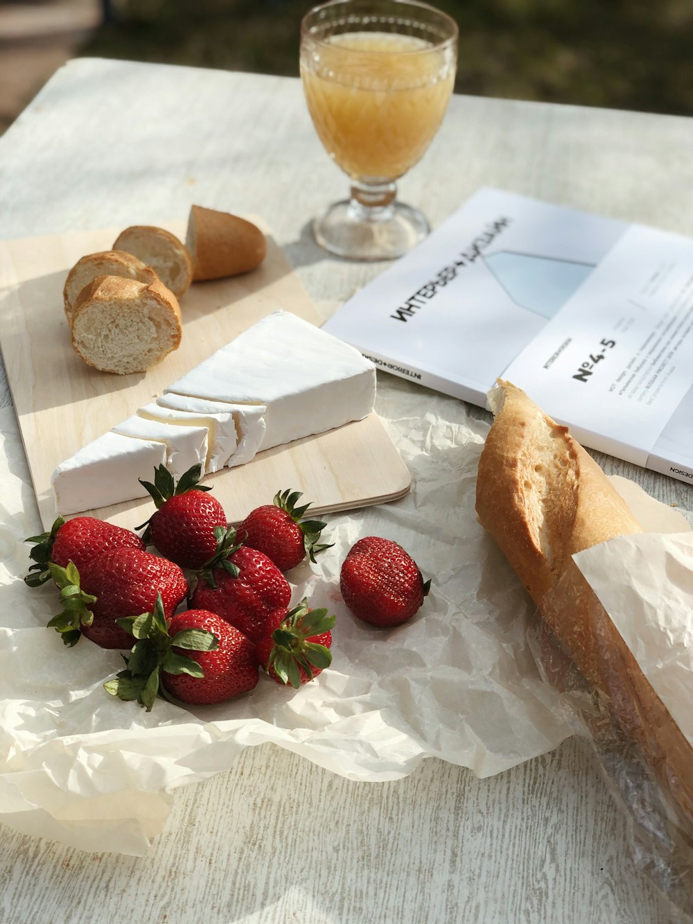 strawberries on white paper beside clear wine glass