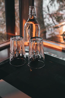 Refreshing glass bottles filled with natural fruit juices glowing in soft light