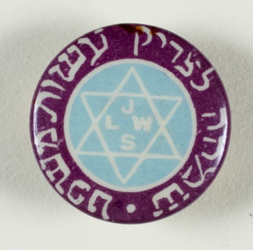 A circular button or badge features a Star of David in the center with the letters 'J L W S' inside the star. The star is enclosed by a blue circle and surrounded by purple with white script or lettering around the edge.