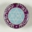 A circular button or badge features a Star of David in the center with the letters 'J L W S' inside the star. The star is enclosed by a blue circle and surrounded by purple with white script or lettering around the edge.
