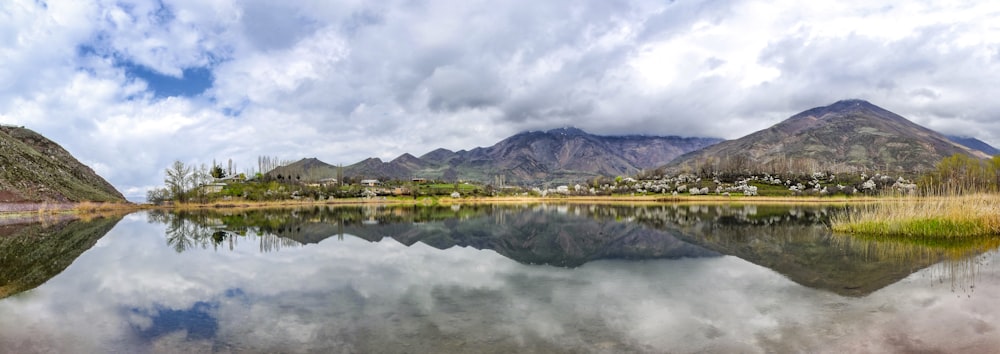 body of water near mountain under cloudy sky during daytime