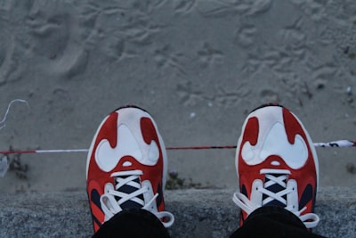 A pair of trendy sneakers resting on a concrete ledge with graffiti art behind.