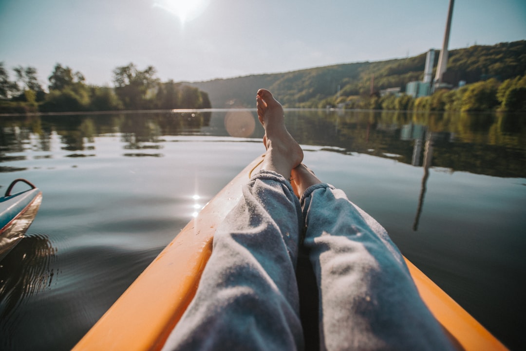 person in blue denim jeans sitting on yellow kayak