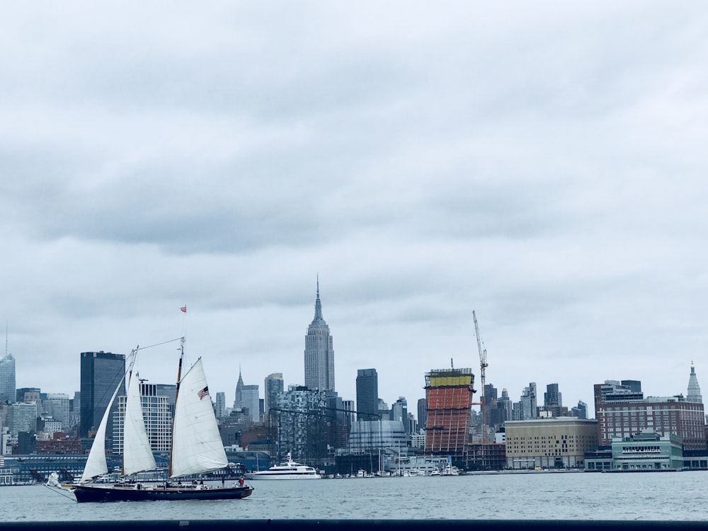 white sail boat on water near city buildings during daytime