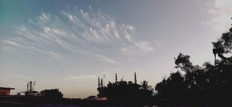A serene blue sky over a peaceful village representing the calm spirit of جمعية تطاون أسمير.