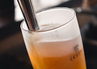 Close-up of a frosty Kompas beer tap pouring golden beer into a glass with creamy foam.