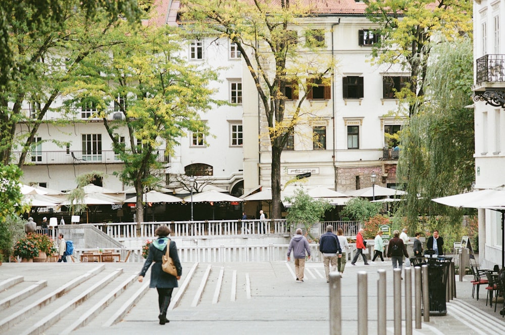 people walking on sidewalk near white concrete building during daytime