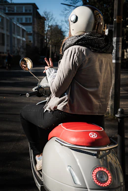 person in brown long sleeve shirt riding on red and white motor scooter during daytime