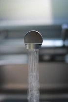 Close-up of a plumber from ican home services repairing a kitchen sink faucet.