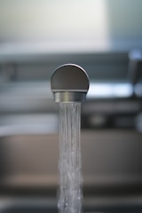 Close-up of clear water flowing from a kitchen faucet into a glass.