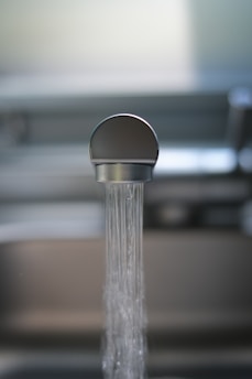 Close-up of clear water flowing from a kitchen faucet into a glass.