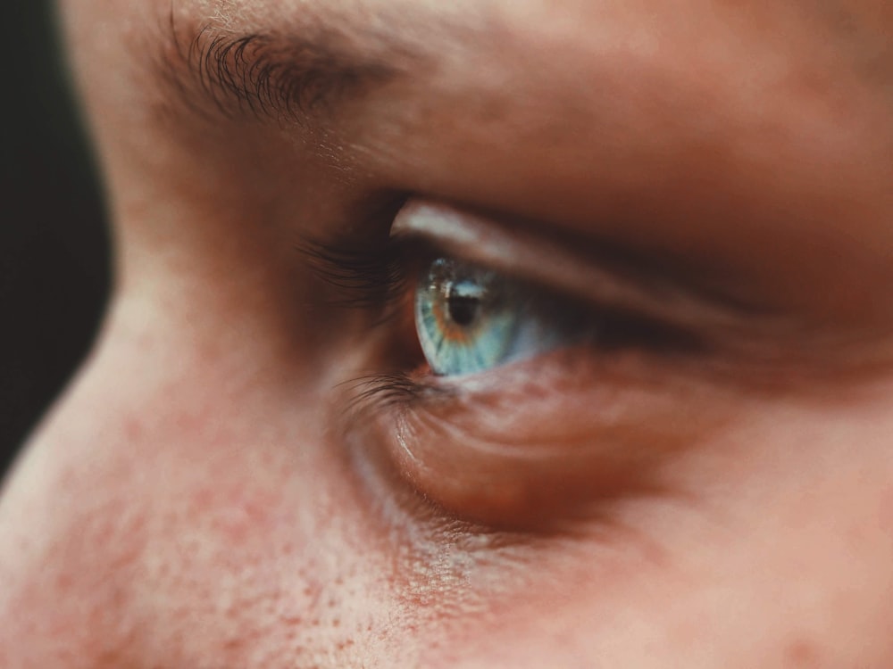 persons blue eye in close up photography