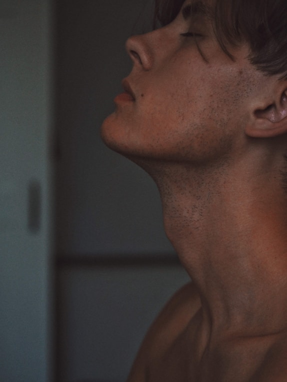 topless man near white wall