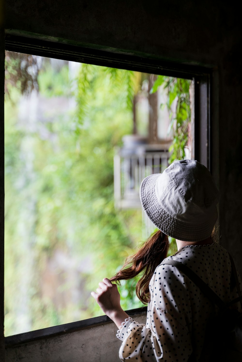 woman in white and black polka dot shirt standing near window