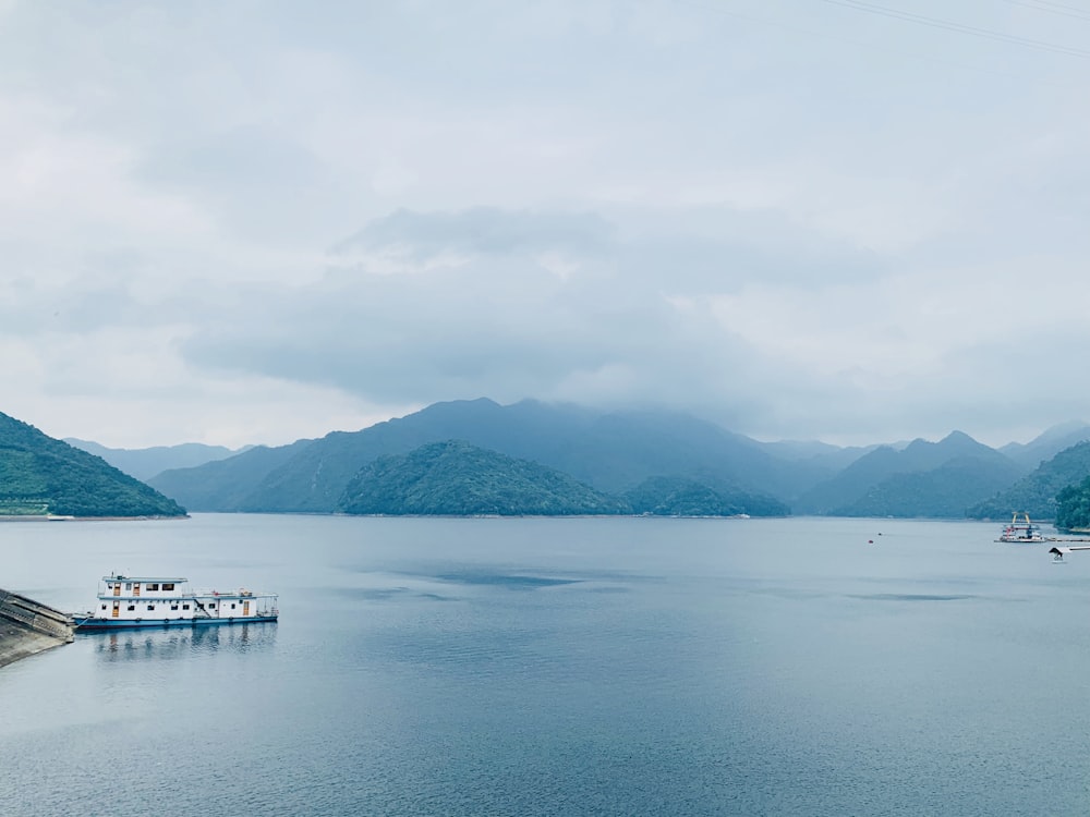 white boat on sea near mountain during daytime