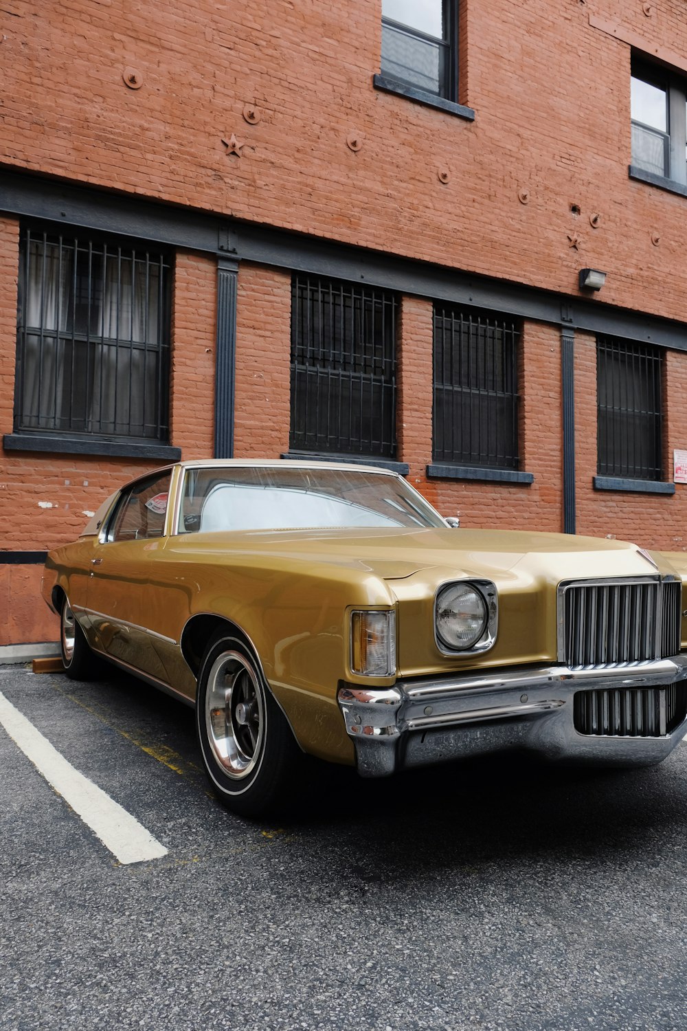 Coche clásico amarillo aparcado junto a un edificio marrón durante el día