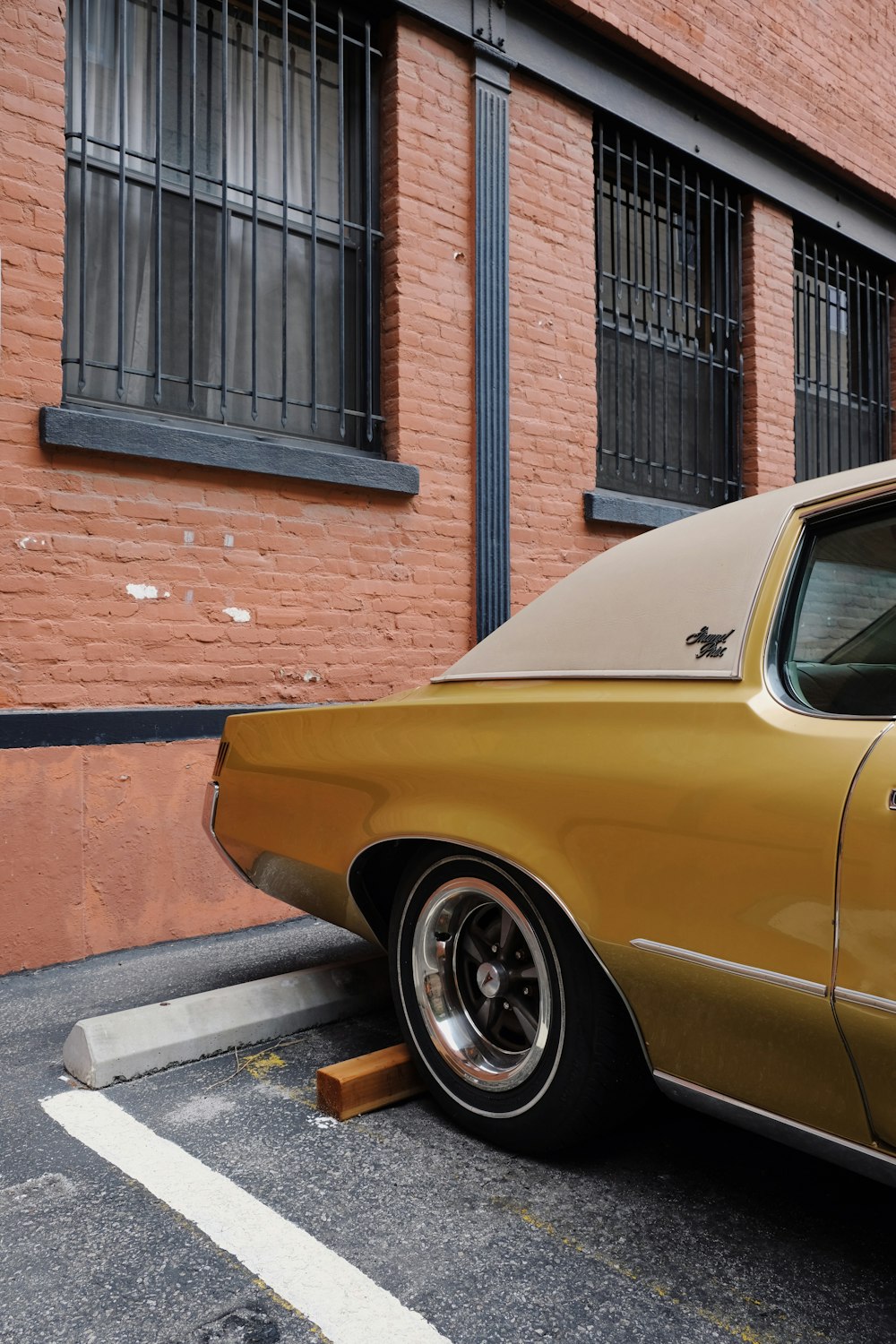 Coche amarillo aparcado junto a un edificio de ladrillos marrones