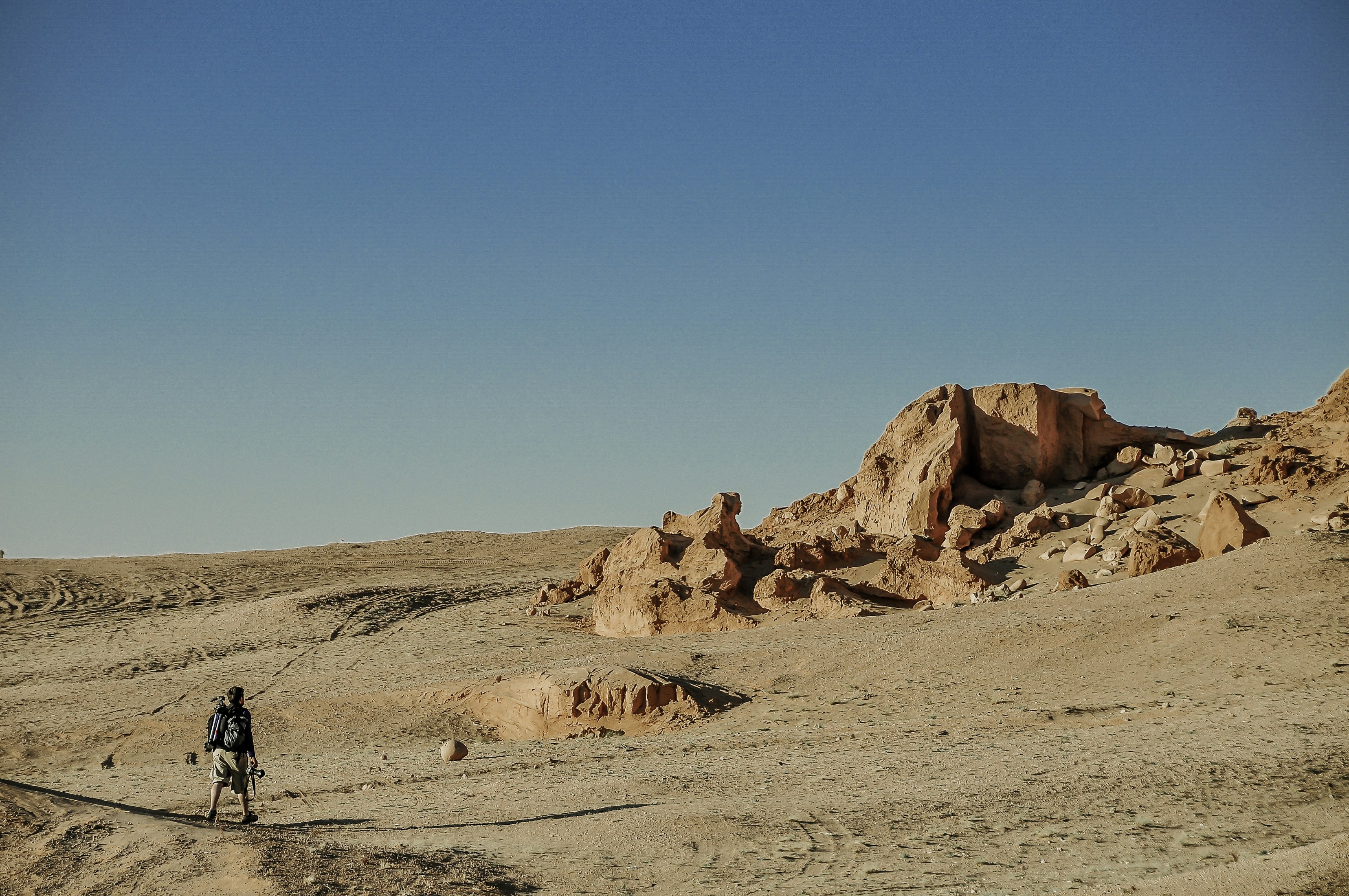 man in black jacket walking on brown sand during daytime