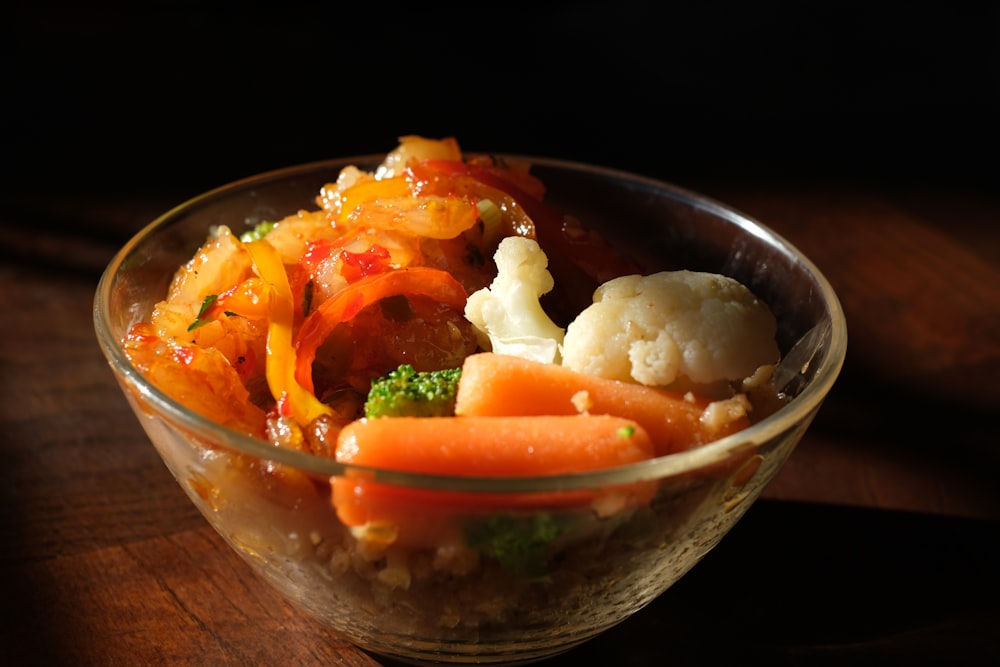 riz cuit avec des carottes tranchées et des légumes verts dans un bol en verre transparent