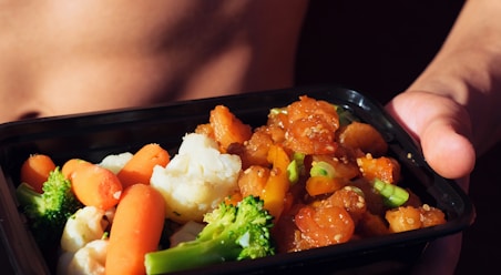 person holding black plastic container with food