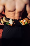 topless man in black shorts holding cooked food