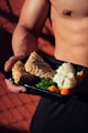 person holding cooked food on black tray