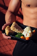 person holding cooked food on black tray