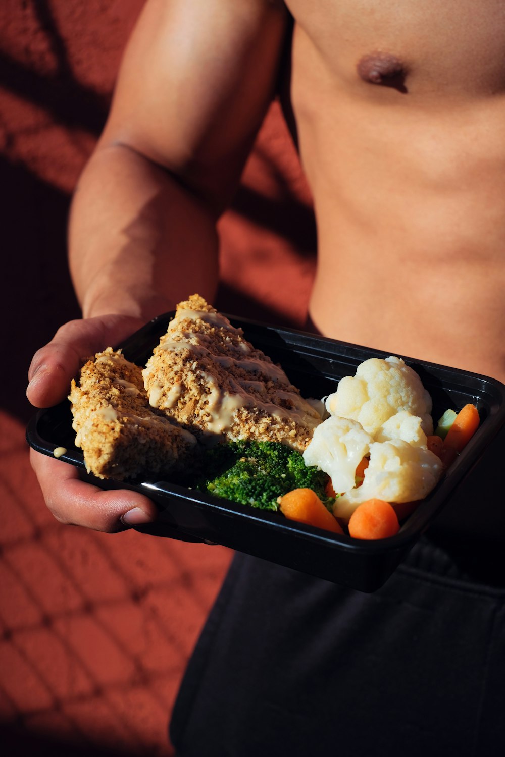 person holding cooked food on black tray