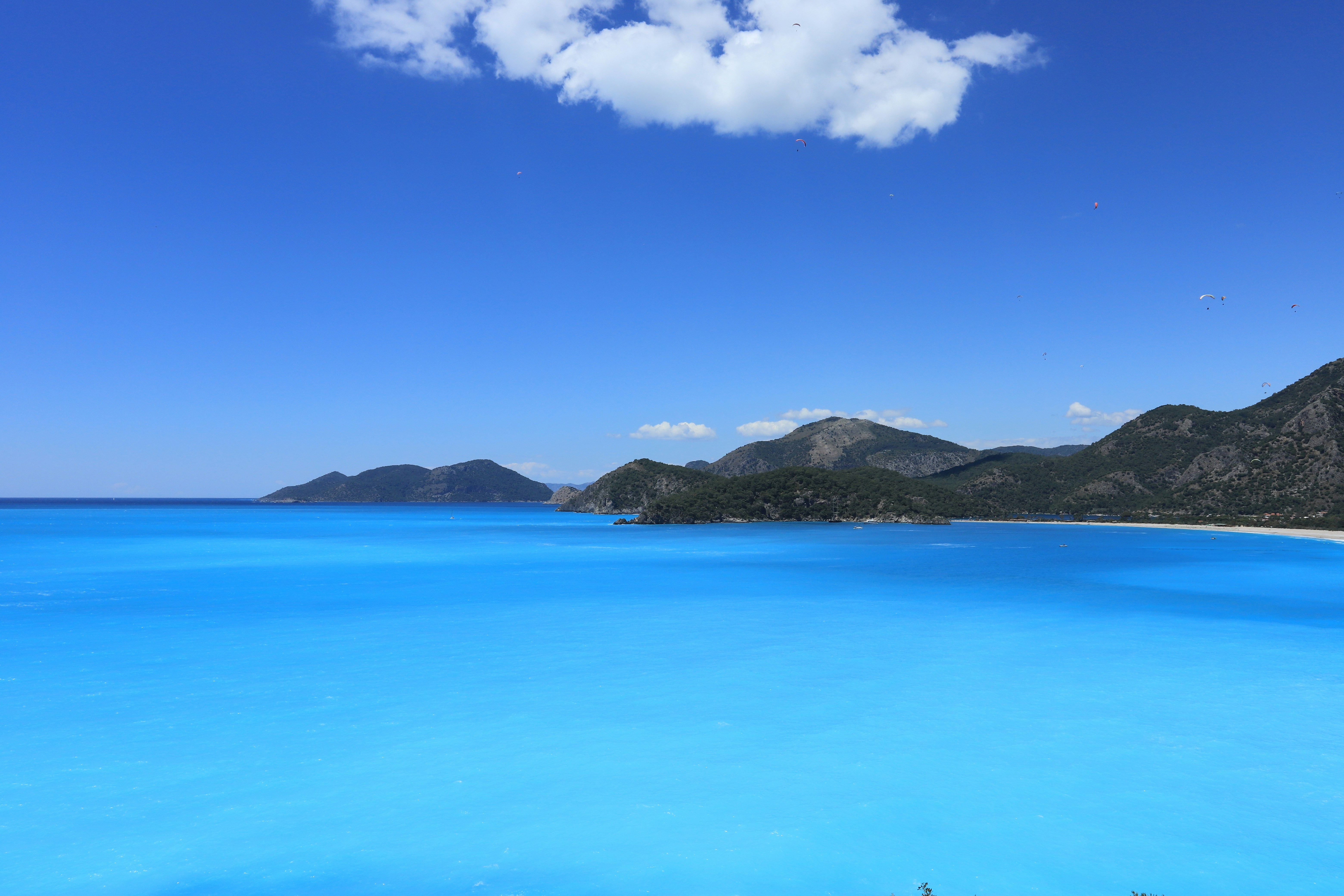 blue sea near mountain under blue sky during daytime