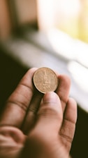 A close-up of hands gently holding a small coin, symbolizing collective effort.