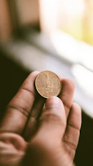 An antique coin displayed in a glass case with soft lighting.