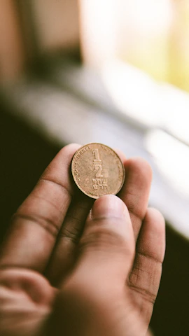 A close-up of a vintage coin resting on an open ancient book, bathed in warm sunlight.