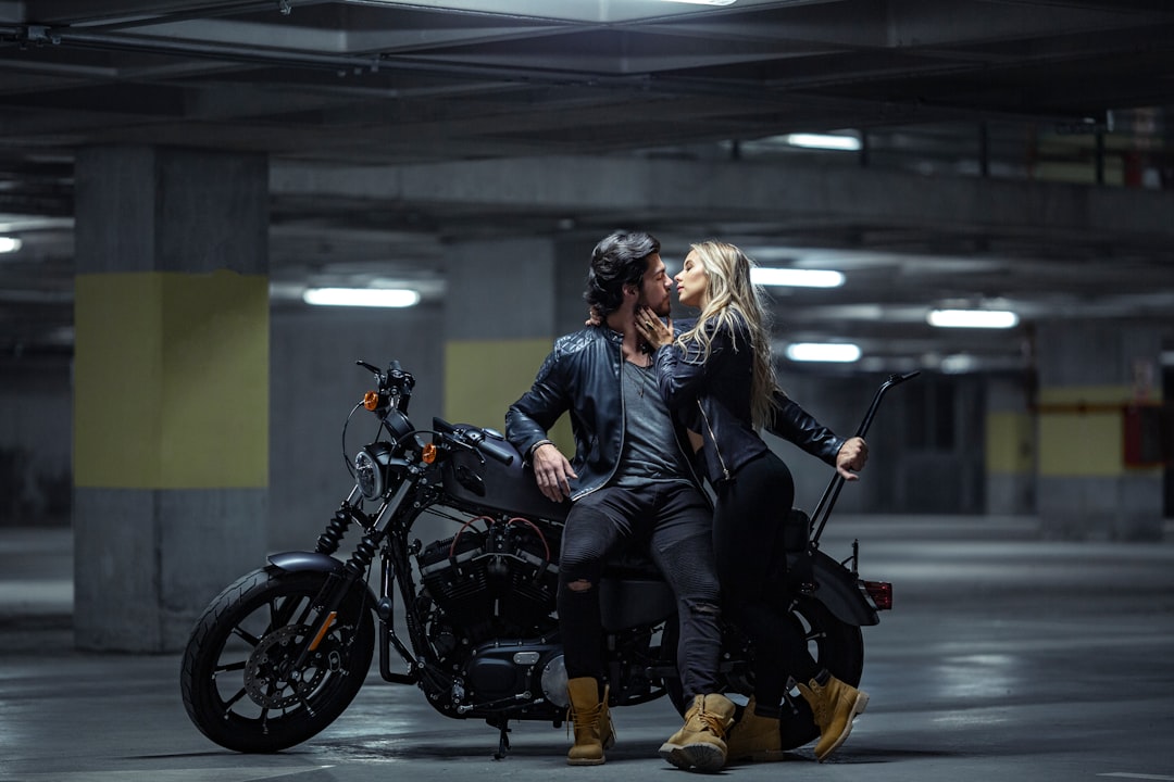 woman in black leather jacket and black pants sitting on black motorcycle