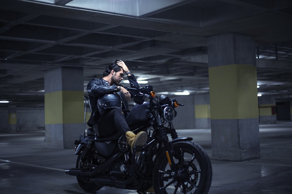 a man sitting on a motorcycle in a parking garage