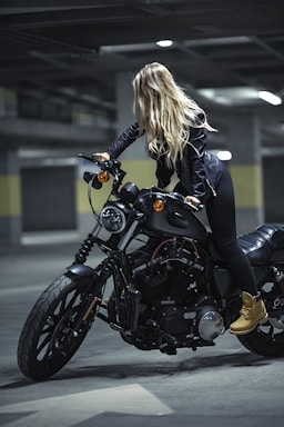 woman in black leather jacket riding black cruiser motorcycle