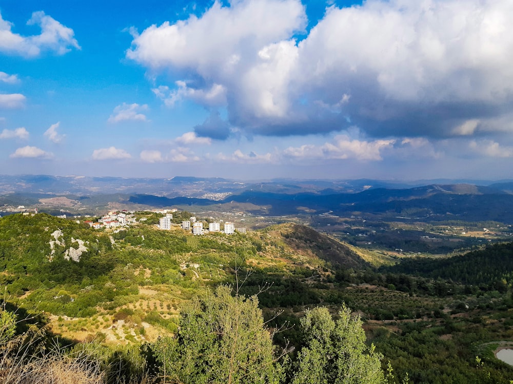 green trees and mountains under white clouds and blue sky during daytime