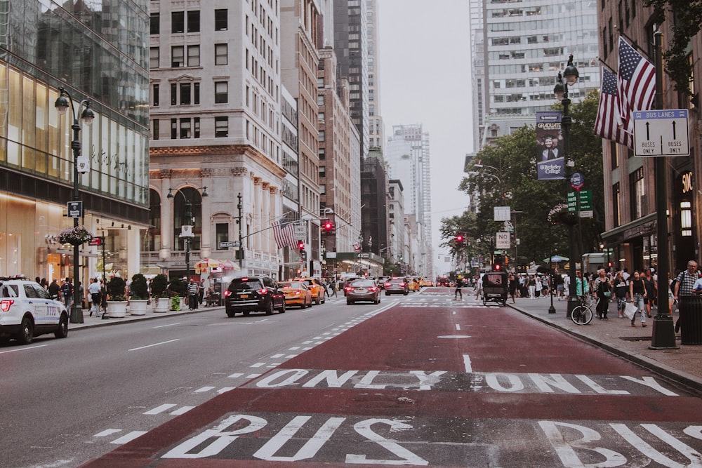 cars on road between high rise buildings during daytime