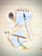 Close-up of a handcrafted knife resting on a wooden table beside a leather-bound notebook and pen.