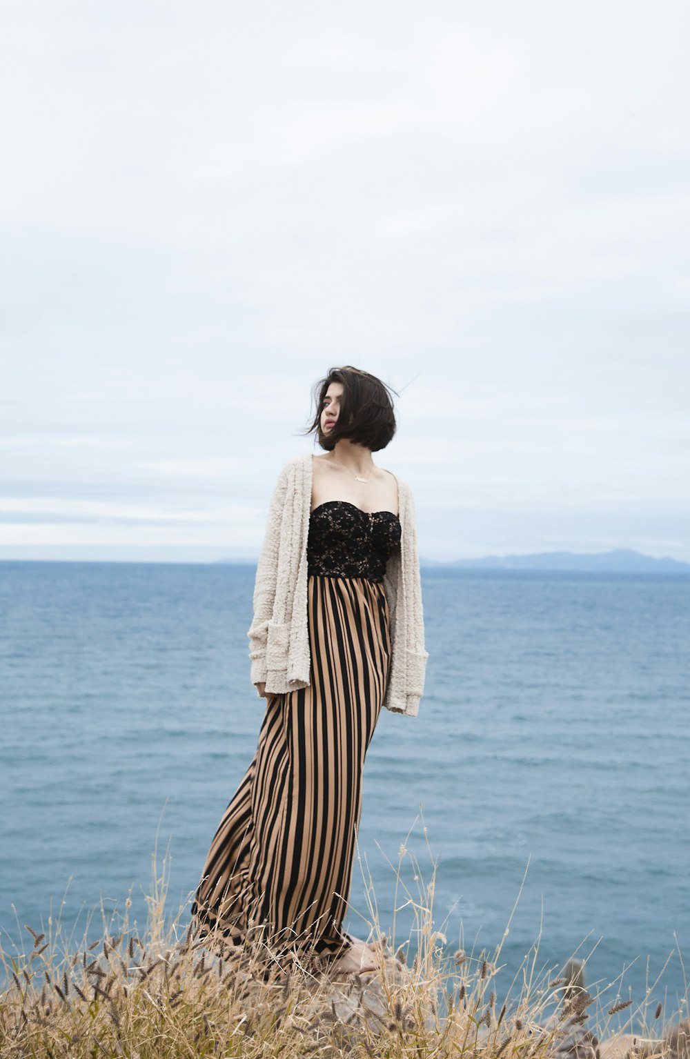 woman in black and white striped dress standing on blue sea during daytime