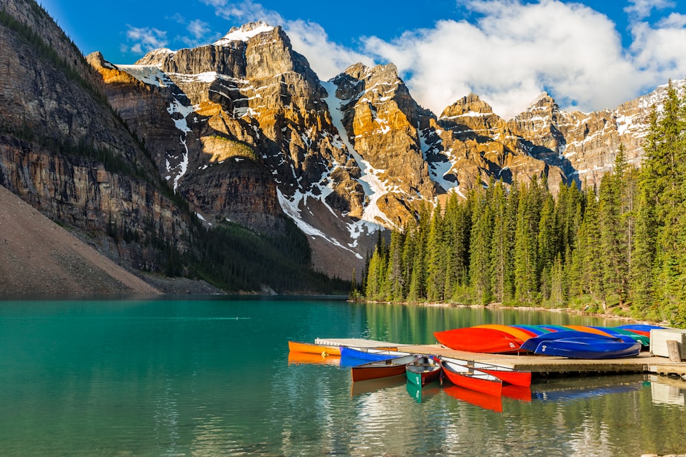 red and blue kayaks on dock near mountain during daytime