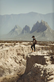A packed backpack resting on a rocky outcrop overlooking a vast desert landscape
