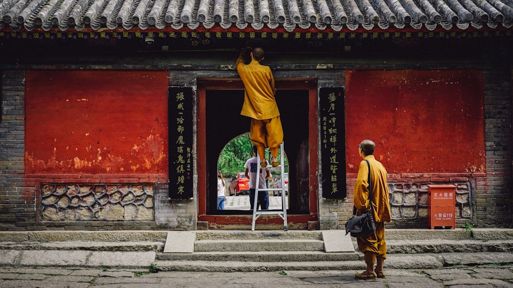 man in yellow robe walking on gray concrete stairs