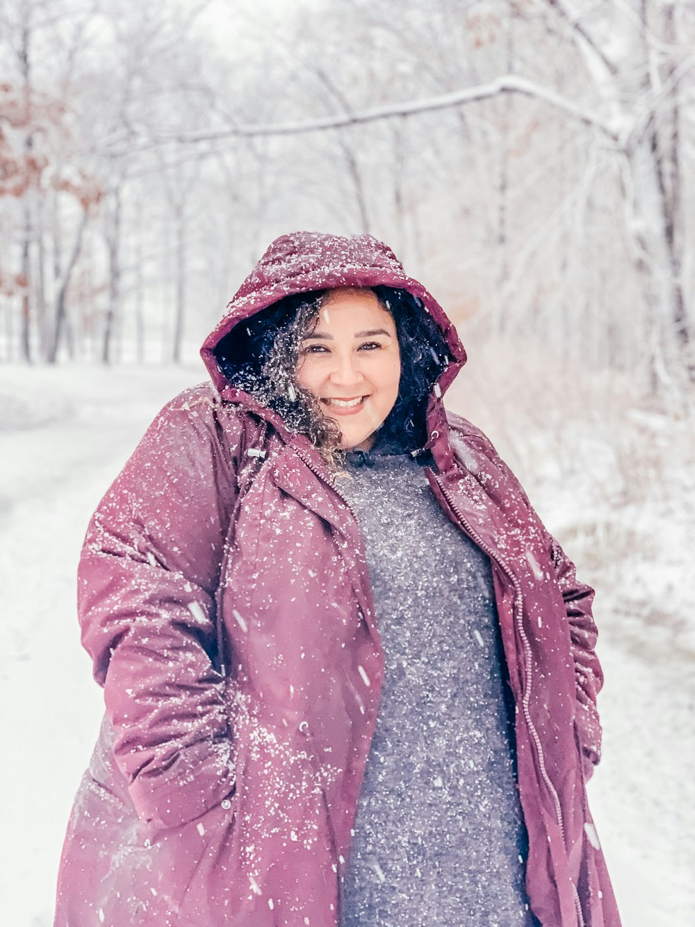 日中、雪に覆われた地面に立つ茶色の冬のコートを着た女性