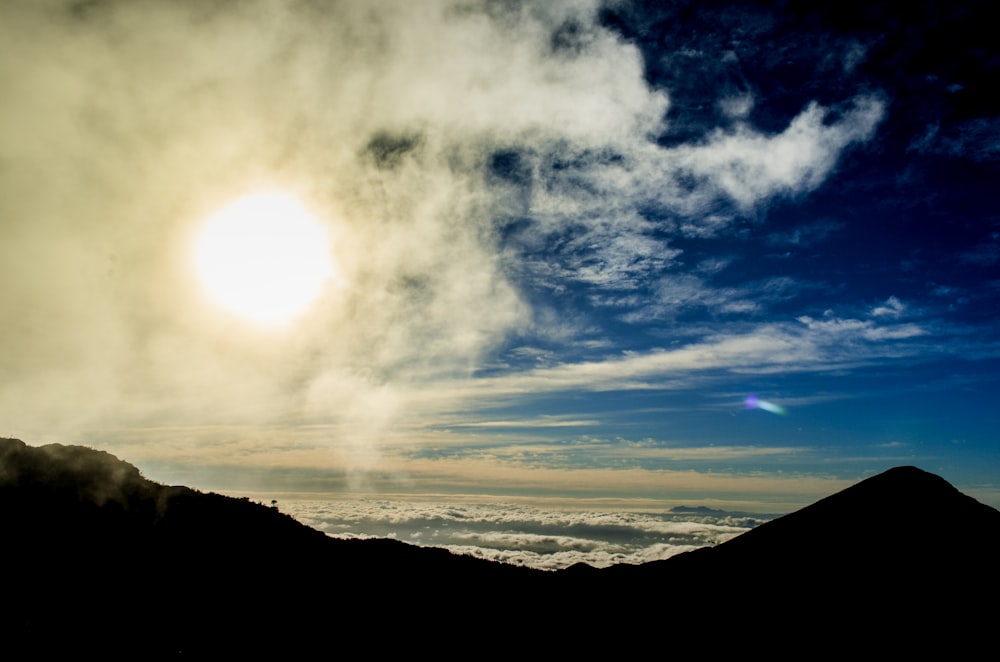 silhouette of mountain under cloudy sky during daytime