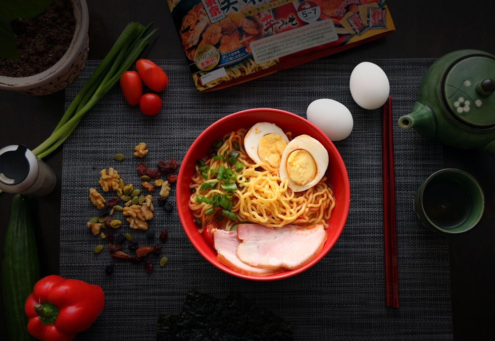 pasta with sliced vegetables on red ceramic plate